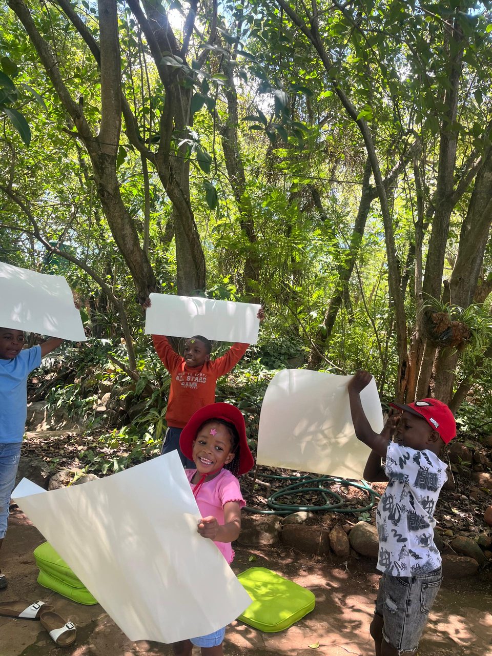 Children holding their artwork in the garden